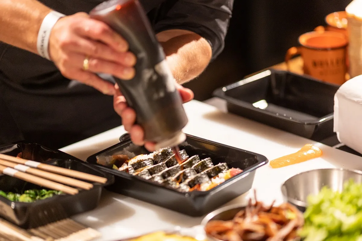 Ręce doprawiają sushi sosem. Czy można jeść sushi karmiąc piersią? To pytanie nurtuje wiele mam.