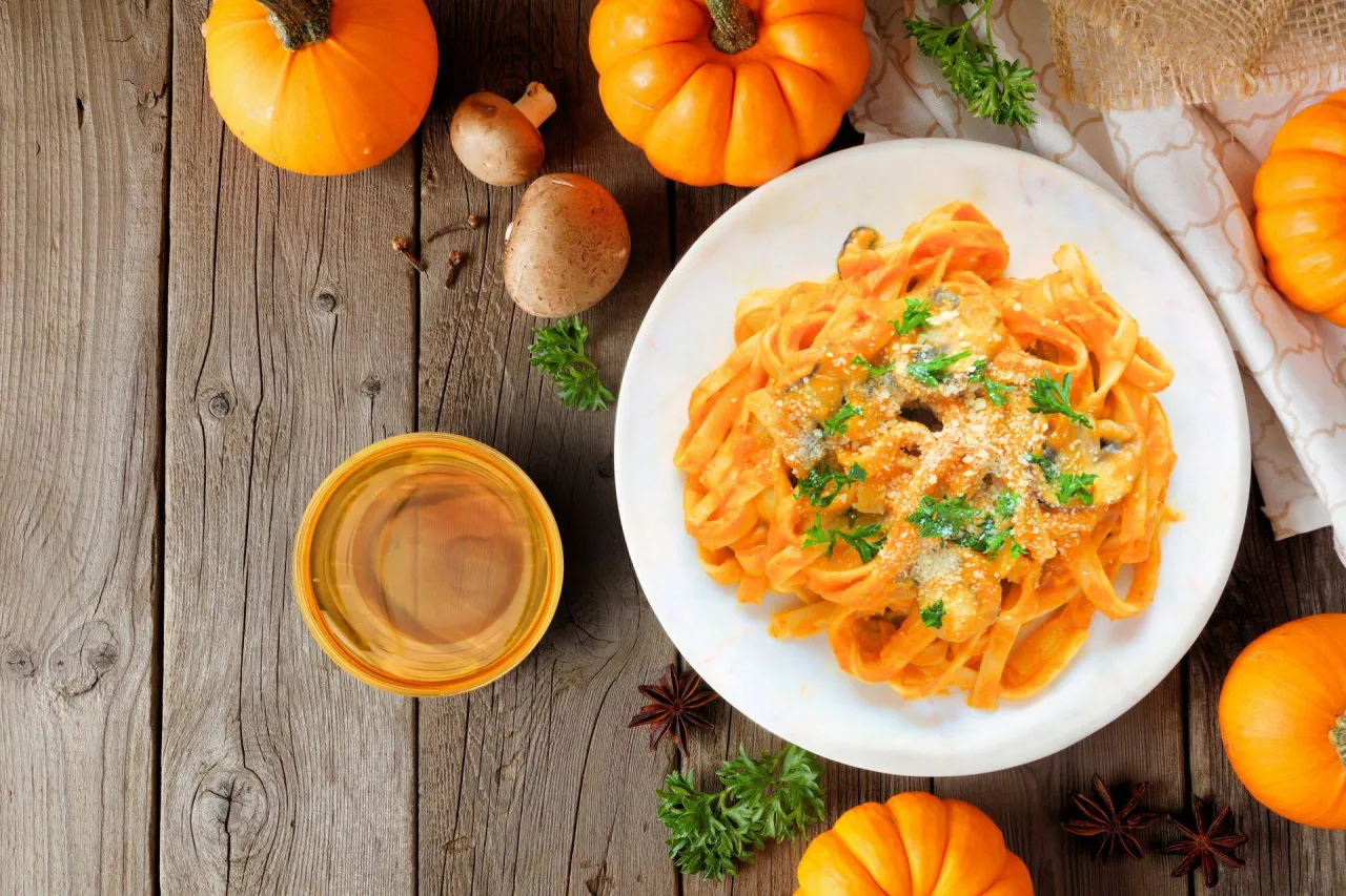 Pyszny makaron z dyni i grzybami, idealny pomysł na to, co ugotować z dyni. Dekoracja z dyni, zi&oacute;ł i przypraw.