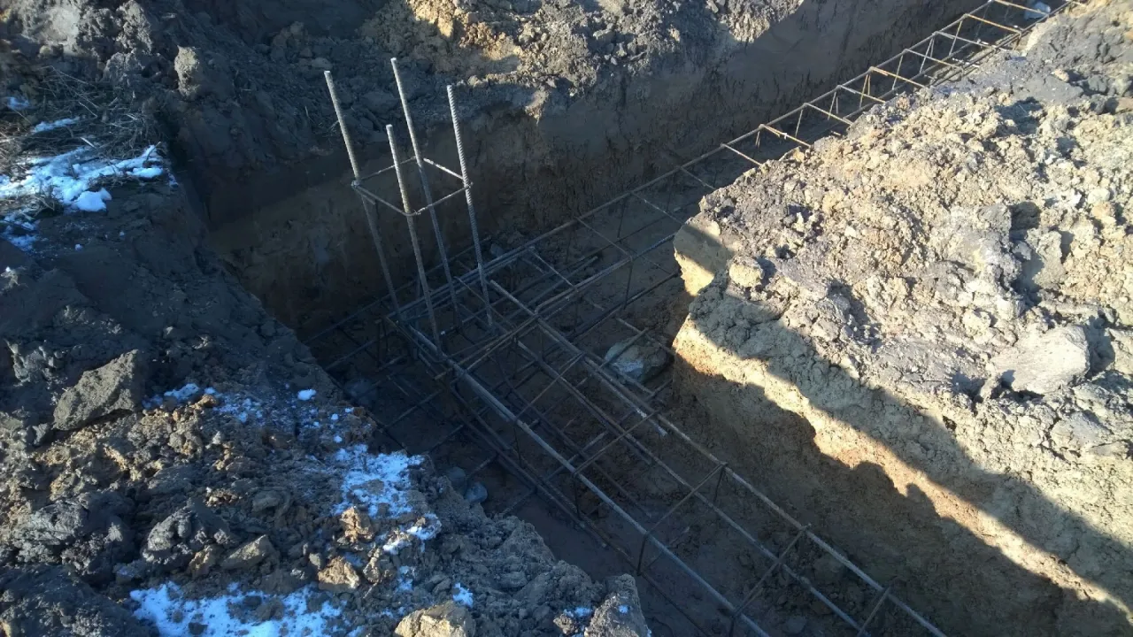 Zbrojenie fundament&oacute;w to kluczowy etap, jak zrobić szalunek pod wylewkę. Widoczna stalowa konstrukcja w wykopie.