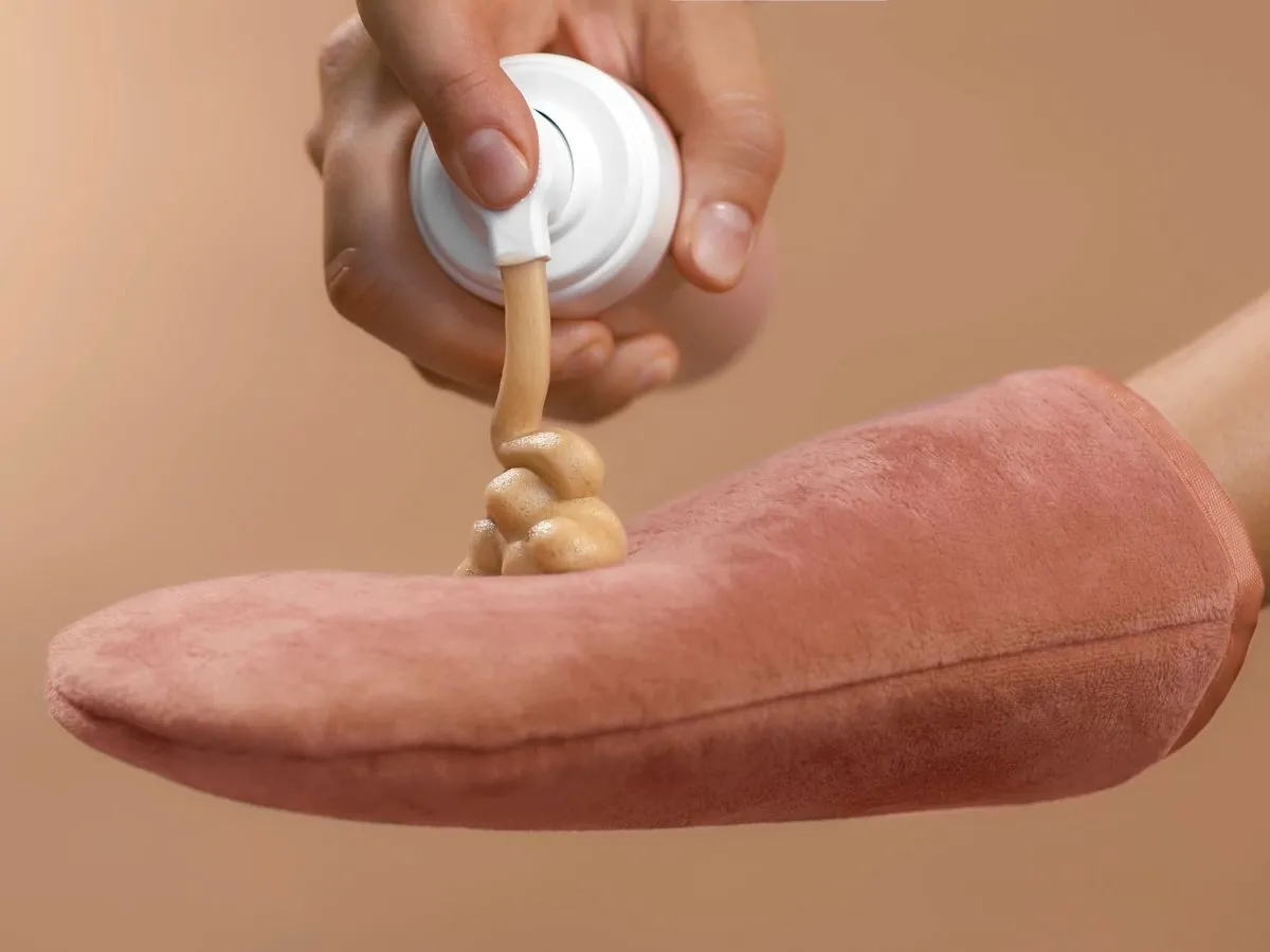 Piana brązująca spływa z dozownika na rękawicę. Idealne rozwiązanie, gdy zastanawiasz się, czym zmyć balsam brązujący.