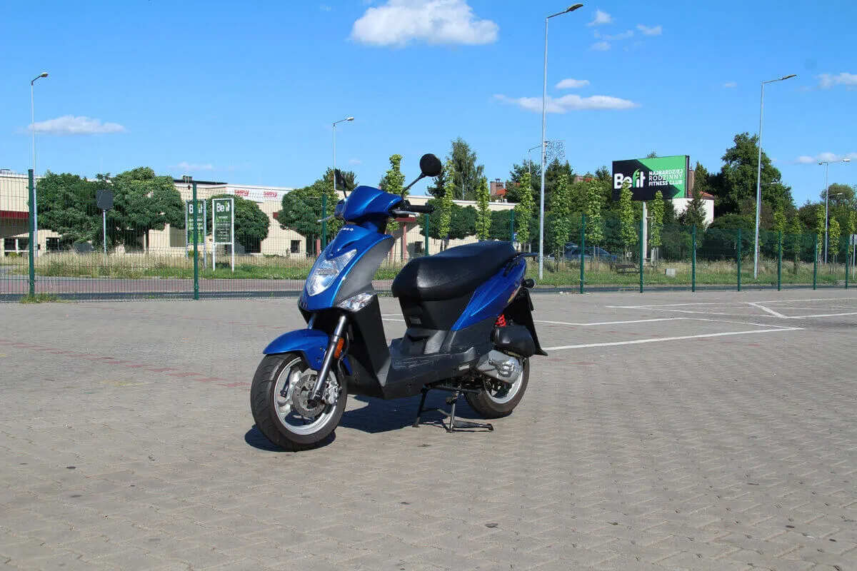 Niebieski skuter na parkingu. Zastanawiasz się, jakie prawo jazdy na skuter jest potrzebne, by nim jeździć?