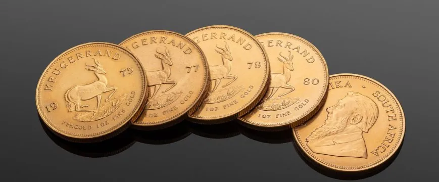 Złote sztabki i monety bulionowe obok siebie