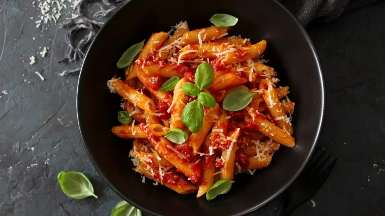 Klassische Nudeln mit Tomatenso&szlig;e und Basilikum auf einem Teller