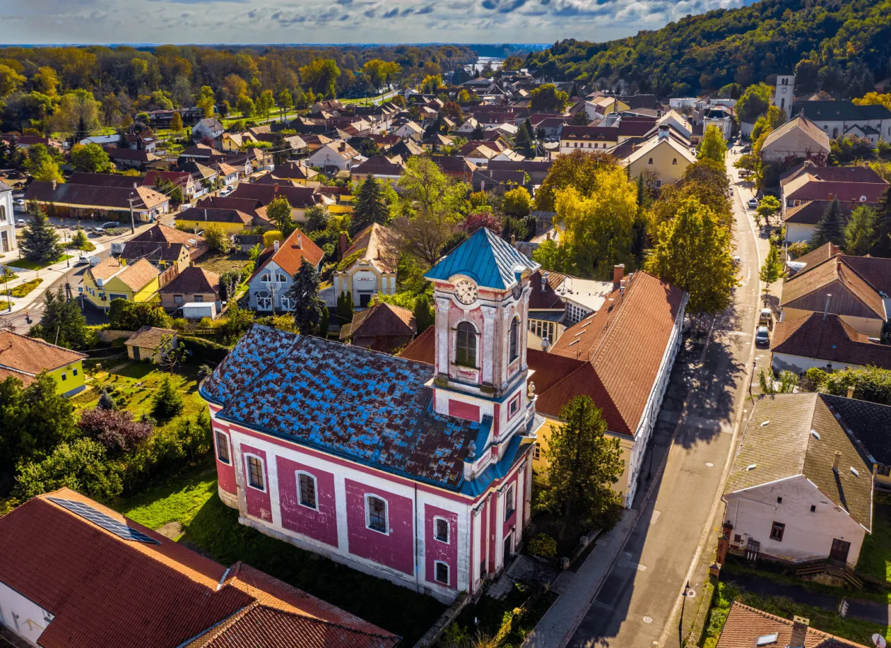 Urokliwy kości&oacute;ł z niebieskim dachem i r&oacute;żową fasadą w malowniczej wiosce na Węgrzech. Węgry najpiękniejsze miejsca.