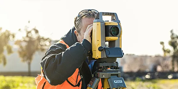 sprzęt geodezyjny tachimetr i odbiornik GPS na statywie w terenie