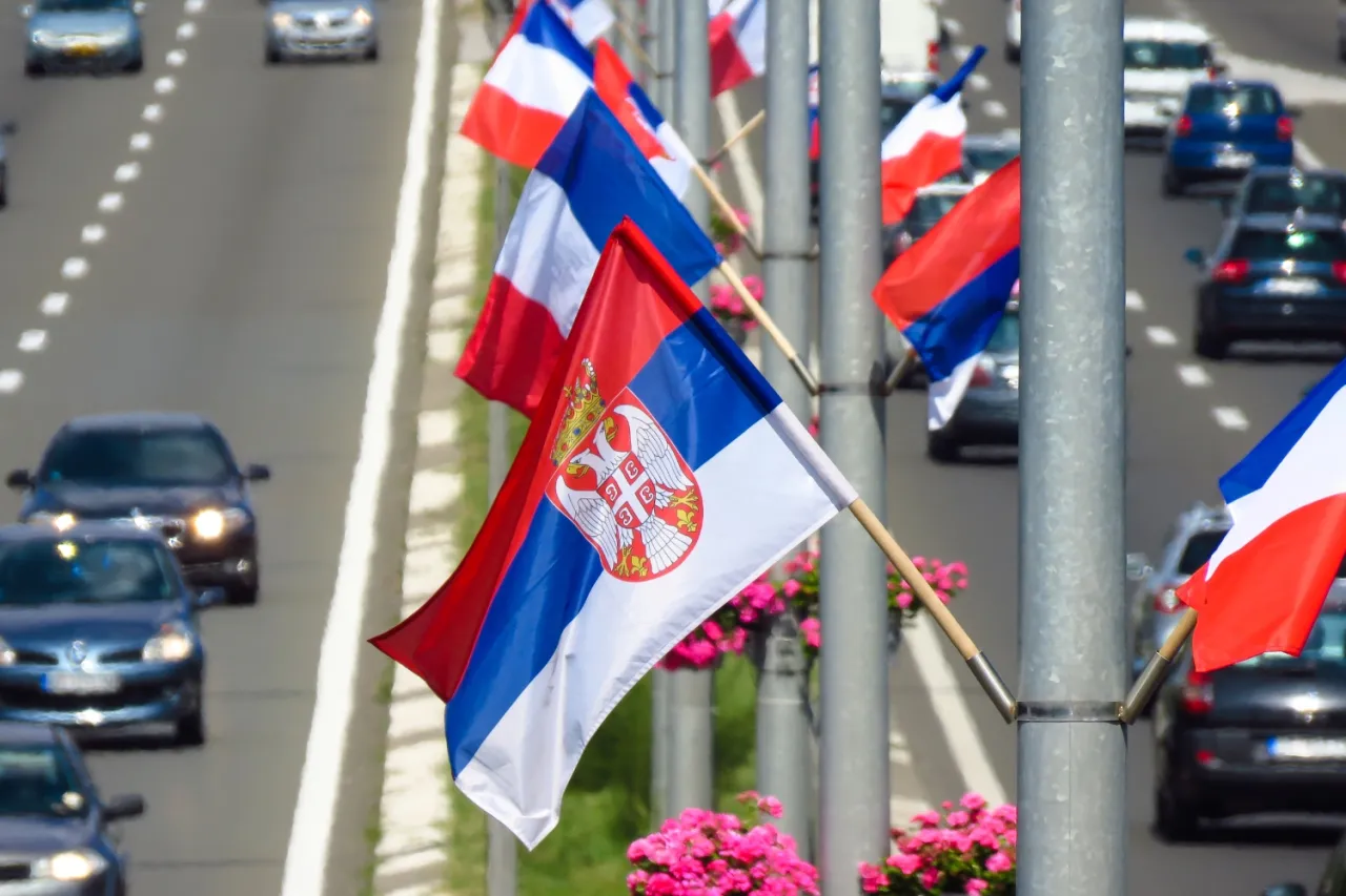 Flagi Serbii i Francji powiewają na wietrze, witając podr&oacute;żnych na wjeździe do Serbii.