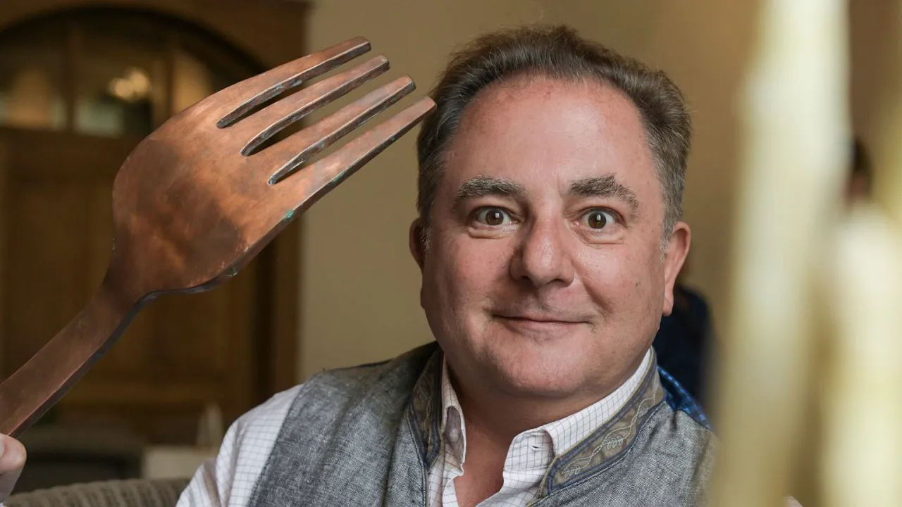 Robert Makłowicz z gigantycznym widelcem, sugerującym, co tak naprawdę znajduje się w składzie sosów Roberta Makłowicza: smak, pasja i dobra zabawa.