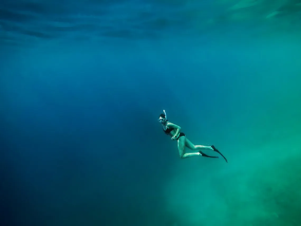 Osoba zanurzająca twarz w wodzie basenowej