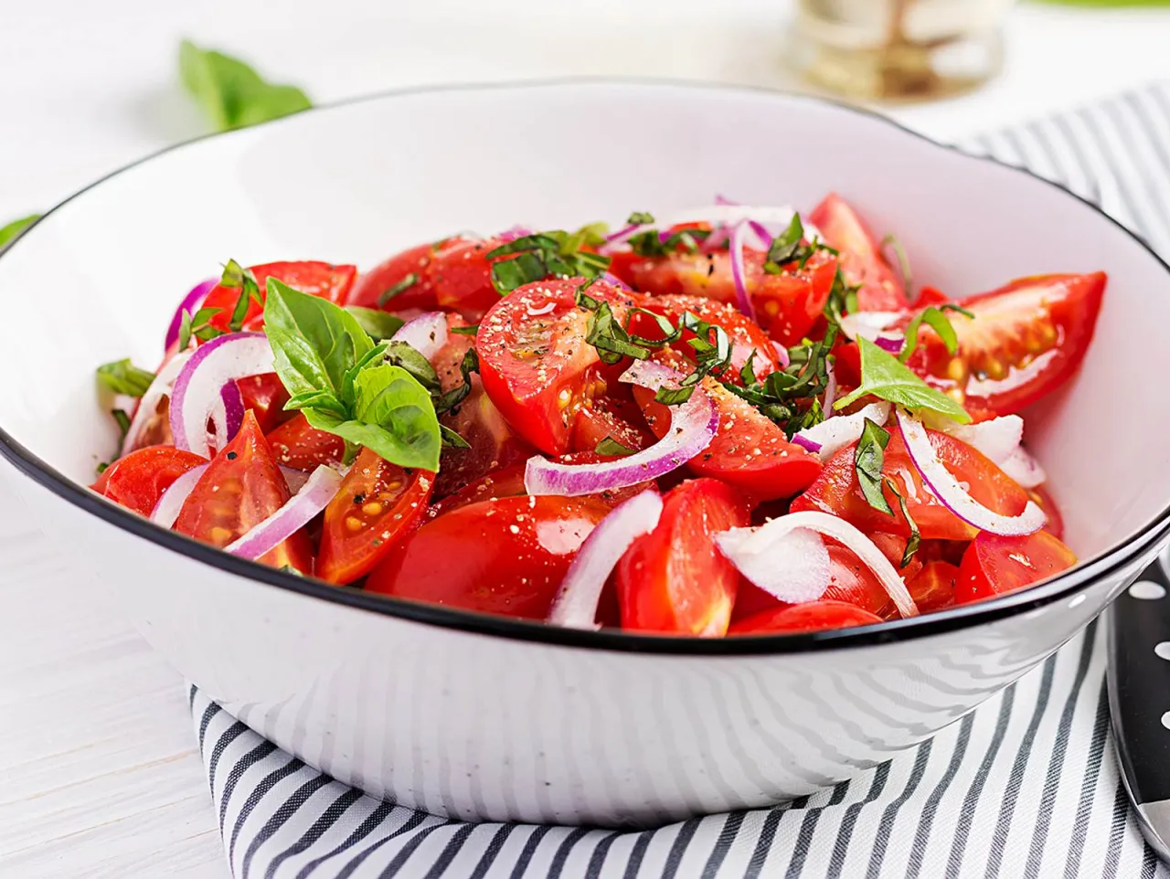 appetitlicher Tomaten Zwiebel Salat in einer Glassch&uuml;ssel mit frischen Kr&auml;utern