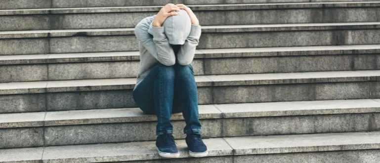 Osoba z objawami lęku społecznego, zmartwiona, trzymająca się za głowę