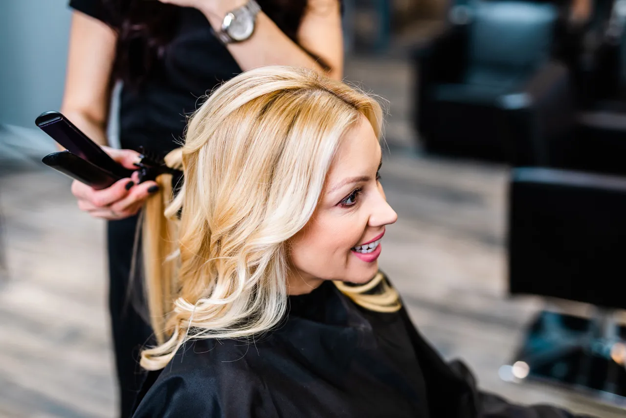 fryzjer stylizuje włosy klientki przed makijażem