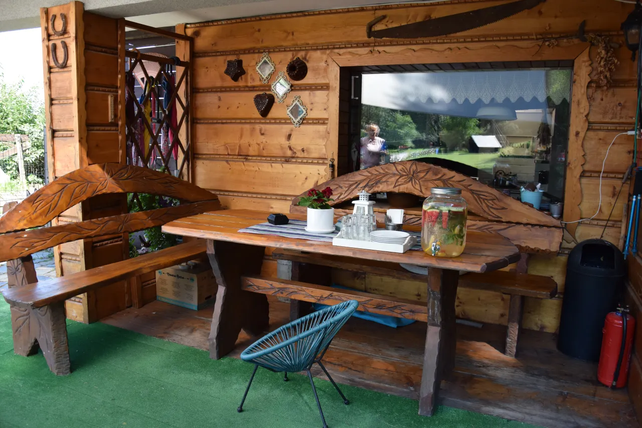 Drewniana altana w stylu agroturystyka bac&oacute;wka giemzik&oacute;w. St&oacute;ł z ławami, dzban z napojem, ozdoby na ścianie.