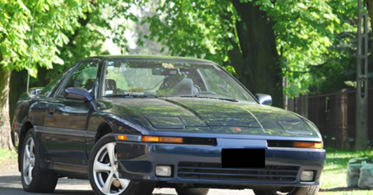 Ciemnoniebieska Toyota Supra z lat 90. na tle zieleni. Zastanawiasz się, ile kosztuje Toyota Supra?