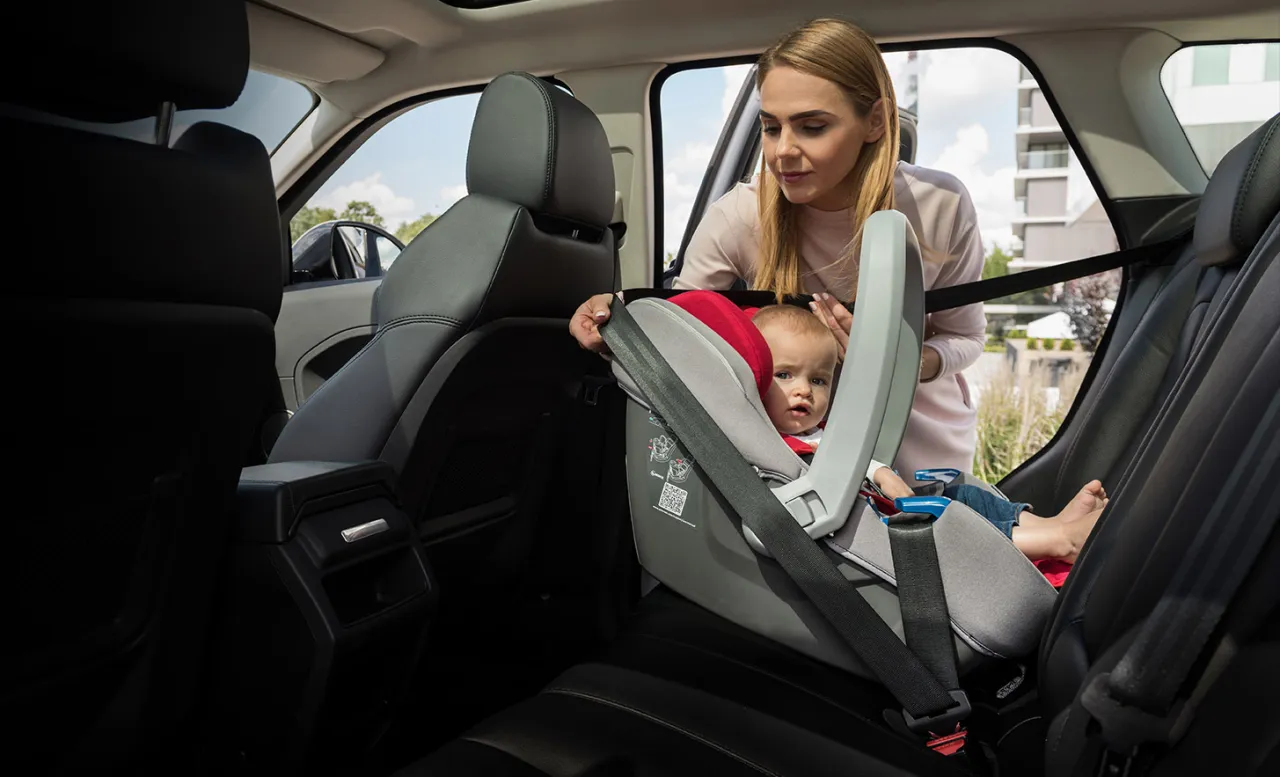 Rodzic montujący pasy w foteliku samochodowym