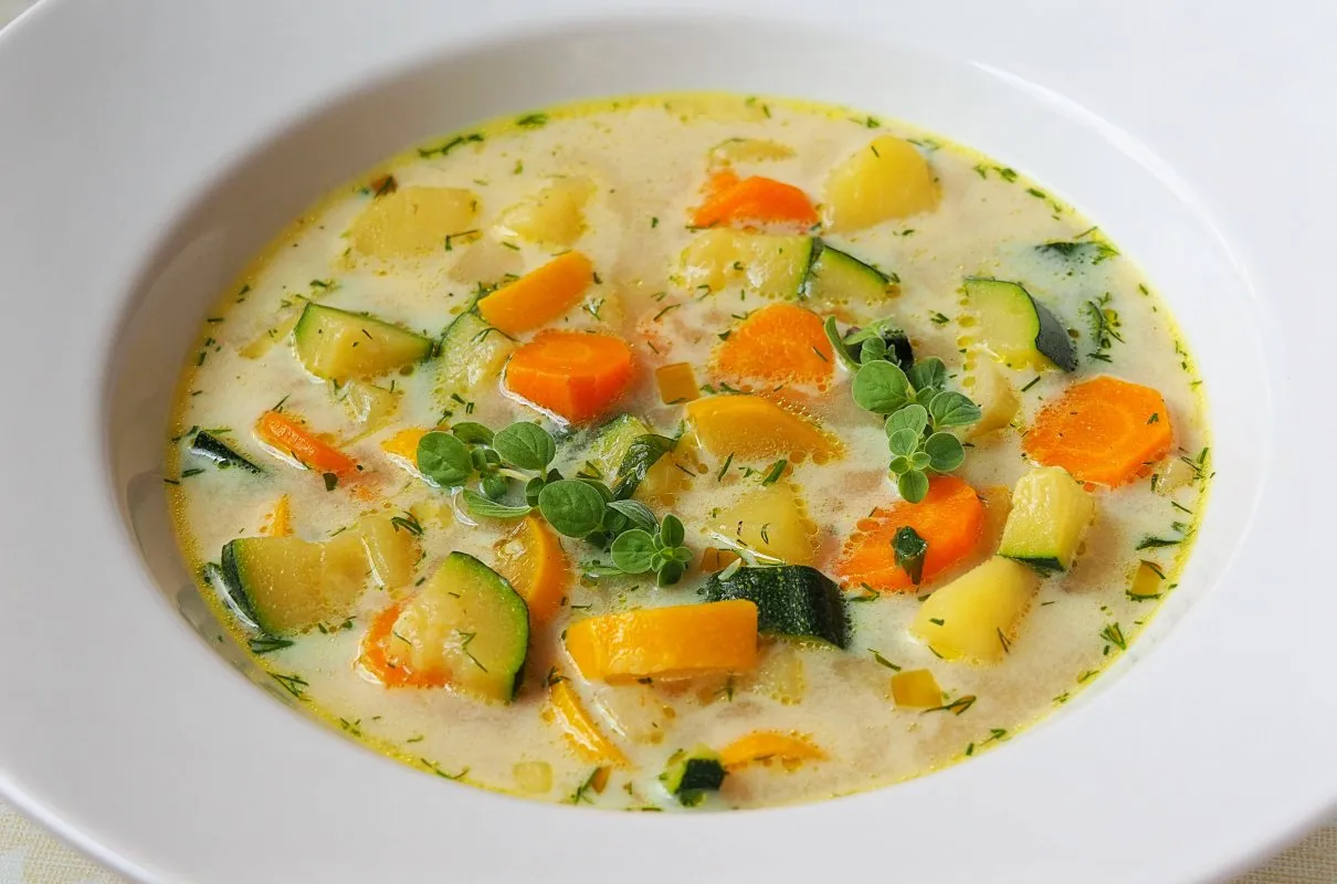Pyszna zupa krem z cukinii, ziemniaków i marchewki. Idealne co z cukinii na obiad, ozdobiona świeżymi ziołami.