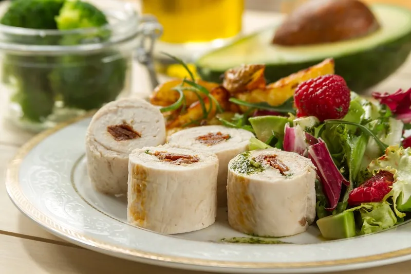 Gotowa rolada drobiowa z suszonymi pomidorami na talerzu