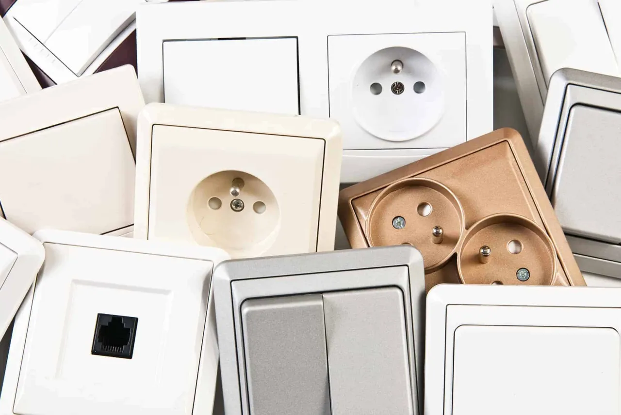 Różnorodne gniazdka i włączniki, w tym te z bolcami, sugerują, jaki prąd jest w gniazdkach – standardowy europejski.