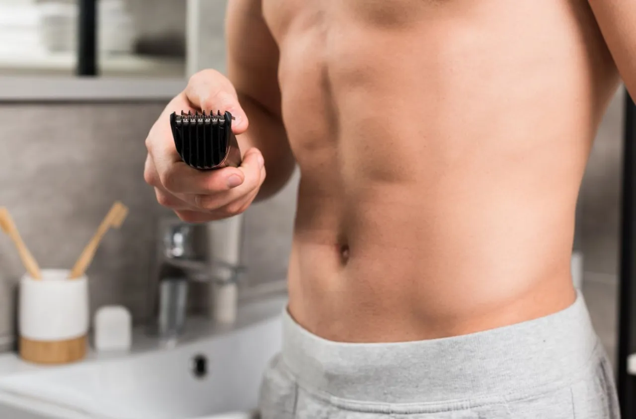 Mężczyzna golący pachy trymerem lub maszynką