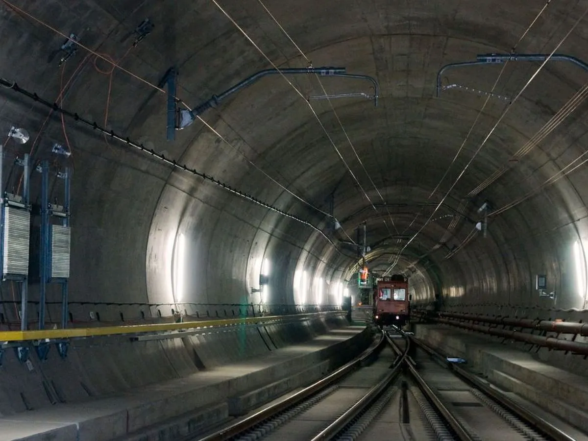 Pociąg wjeżdża do najdłuższego tunelu w Europie. Betonowa konstrukcja, kable i światła tworzą mroczny, ale fascynujący krajobraz.