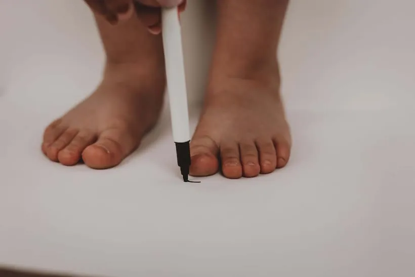 dziecko mierzące stopę na kartce