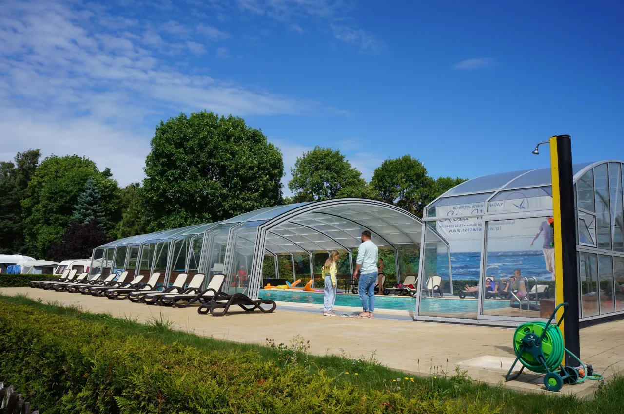 Tanie wczasy nad morzem dla 2 osób z wyżywieniem. Rodzina relaksuje się przy krytym basenie z leżakami i dmuchanymi zabawkami.