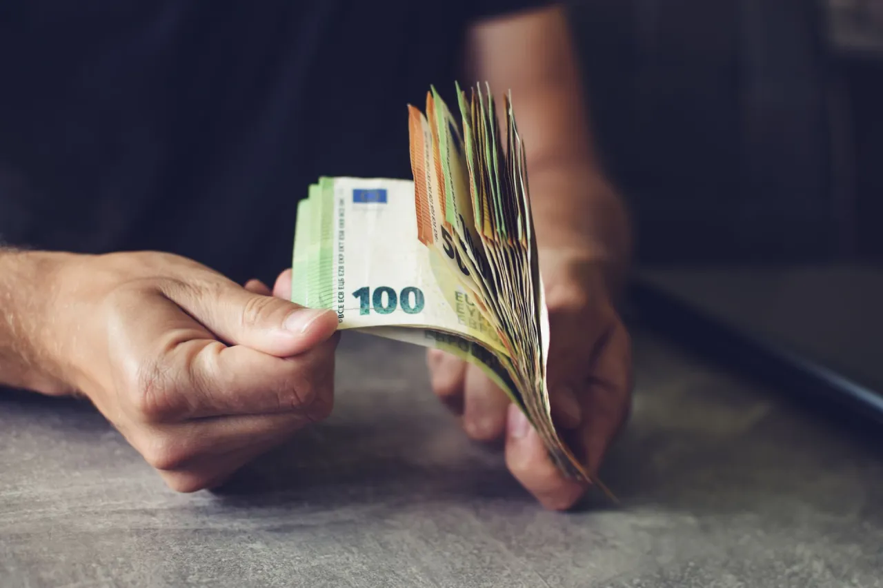 Dłonie trzymają plik banknotów euro. Słowacja jaka waluta? Euro.