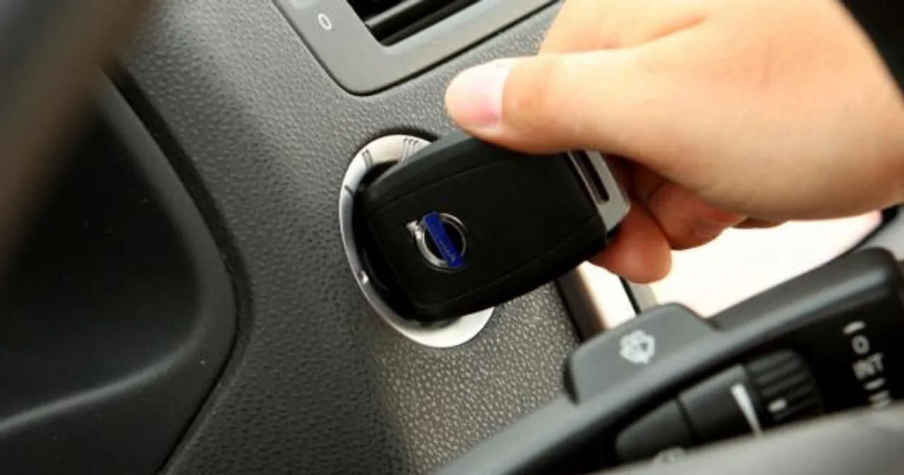 Dłoń wkłada kluczyk do stacyjki, co może być pierwszym krokiem, jak zresetować immobilizer w samochodzie.