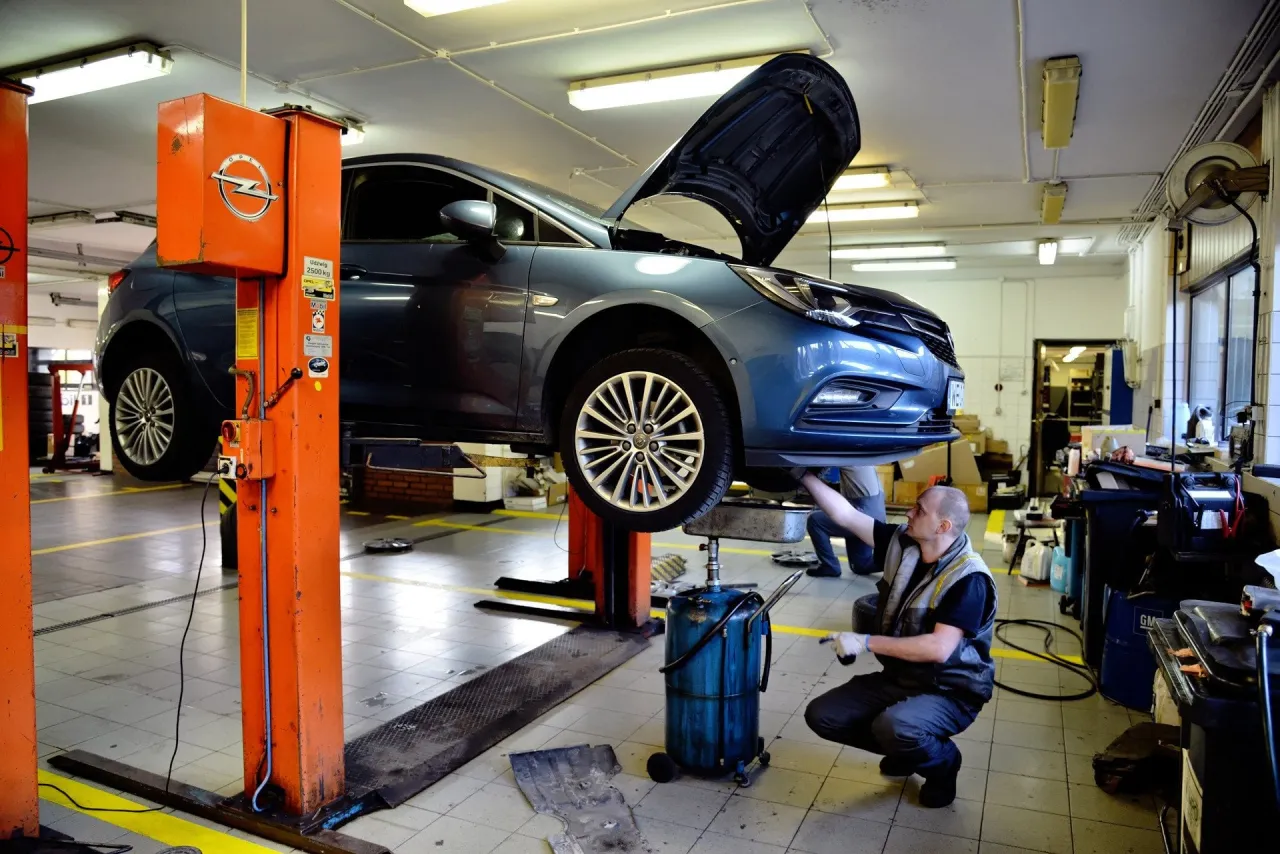 Mechanik wymienia olej w samochodzie na podnośniku. Szybka wymiana oleju to klucz do sprawnego działania auta.