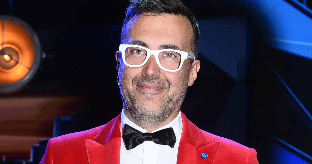 DJ Adamus w czerwonej marynarce i białych okularach, gotowy do zagrania w 