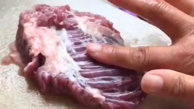 Osoba przygotowująca surowe mięso na desce do krojenia, zachowując higienę