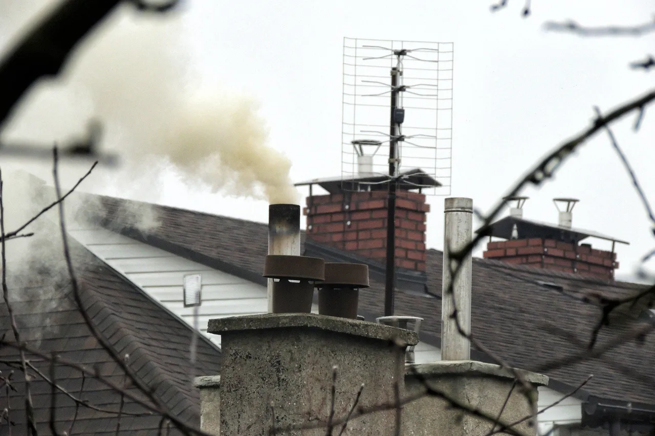 Dym z komina sugeruje, że ktoś zastanawia się, czy można palić kartonami w piecu. Widać kilka kominów i antenę telewizyjną.