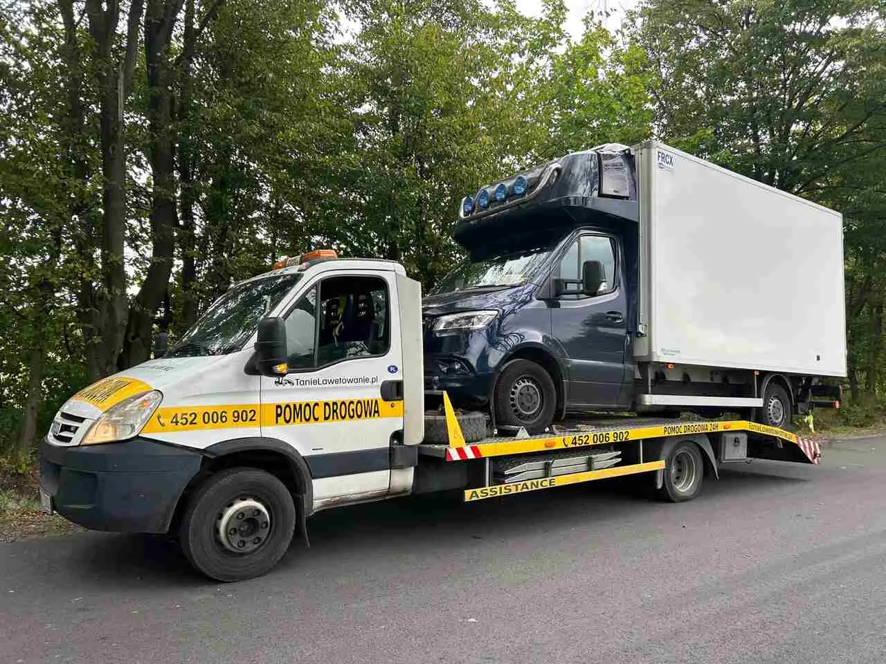 Pomoc drogowa transportuje ciemnoniebieskiego vana. Dowiedz się, ile kosztuje laweta w razie awarii.