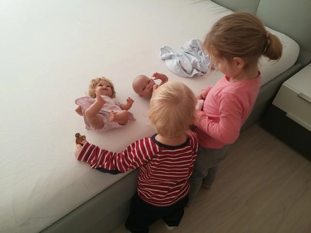 Rodzic bawi się z dzieckiem na macie, dziecko sięga po zabawkę