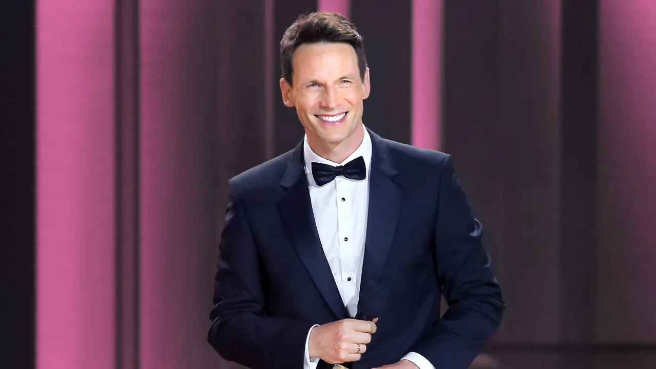 Tomasz Kammel w eleganckim smokingu, uśmiechnięty, gotowy do poprowadzenia kolejnego odcinka 