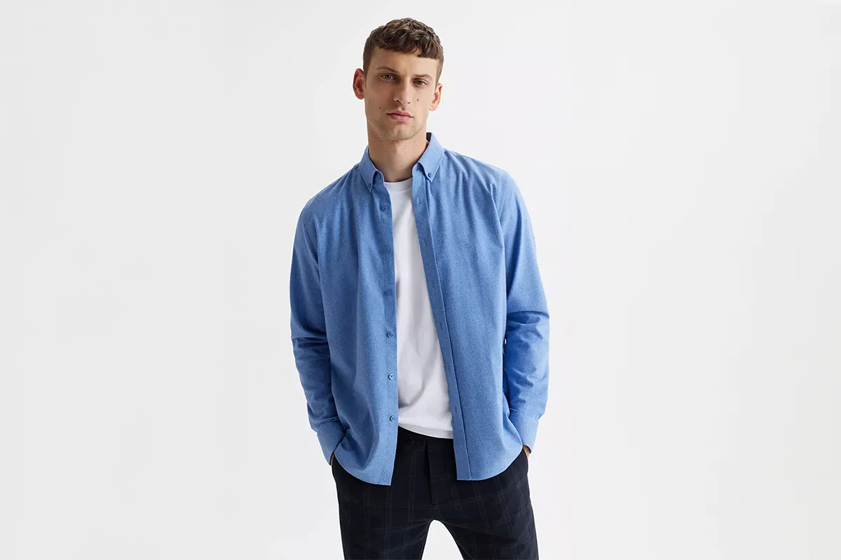 Mężczyzna w niebieskiej koszuli i białej bluzce pod spodem, idealny zestaw jak się ubrać na kabaret.