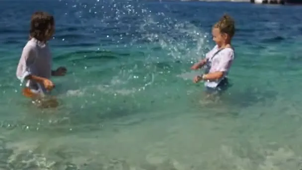 dzieci bawiące się na chorwackiej plaży z butami do wody