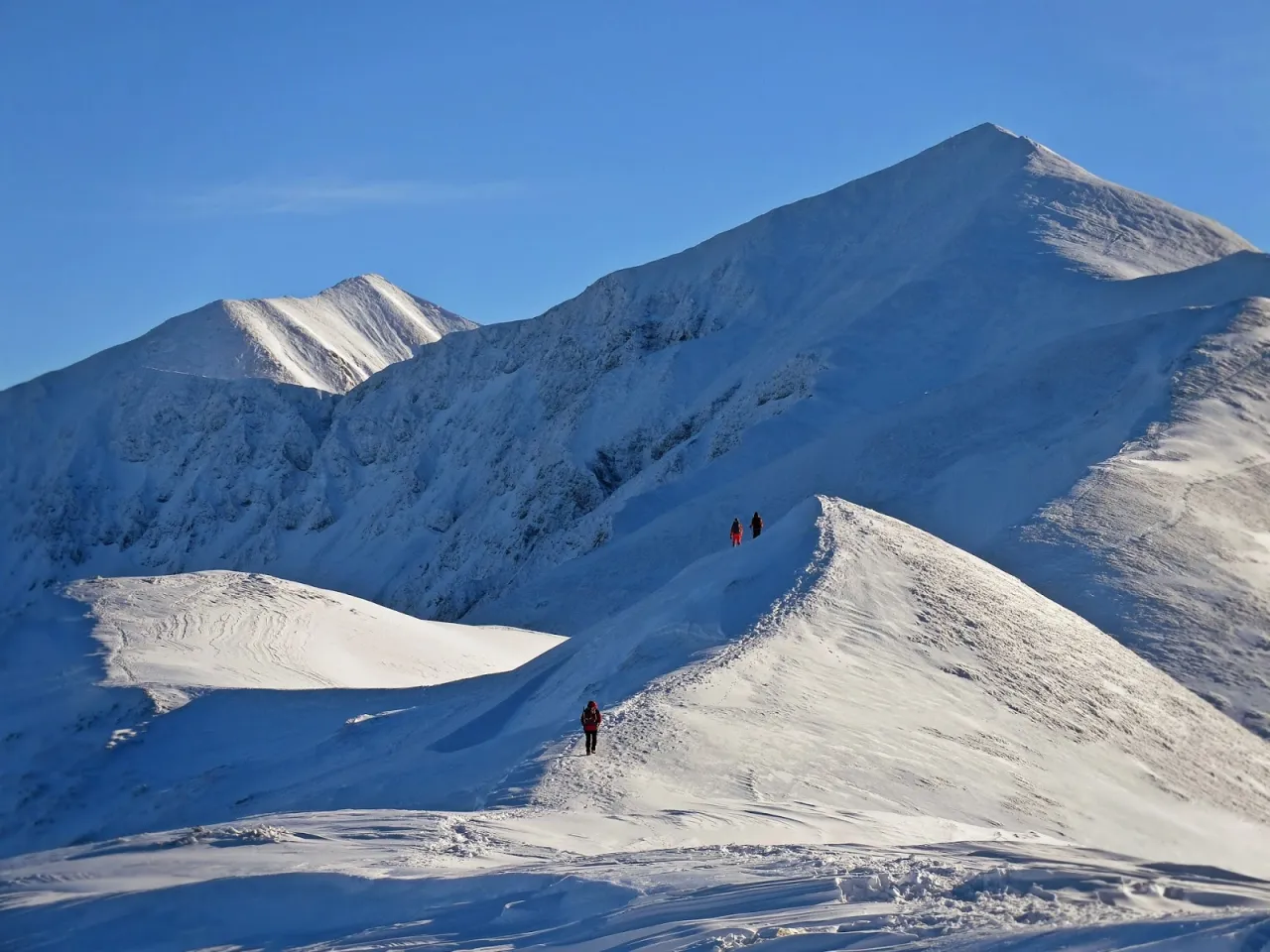 Turyści na ośnieżonym grzbiecie Tatr. Sprawdź, jakie warunki na szlakach w Tatrach panują zimą.