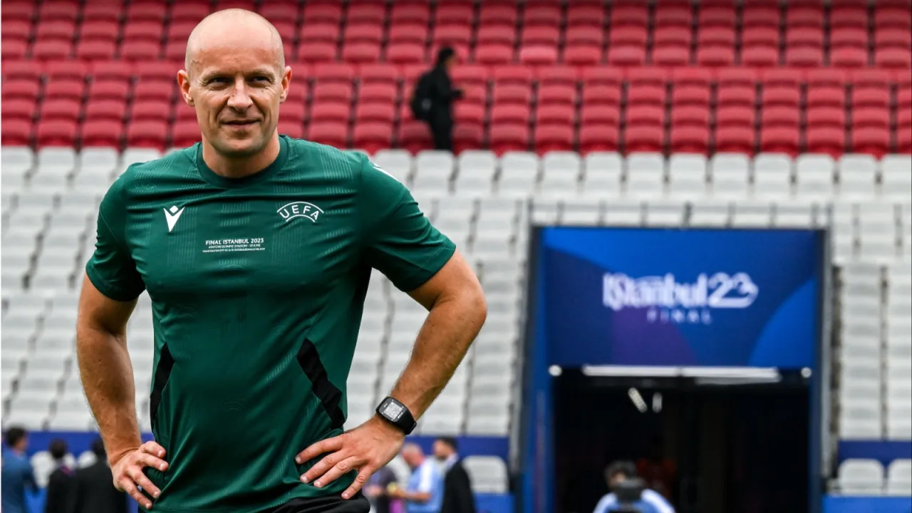 Sędzia w zielonej koszulce UEFA na tle trybun stadionu. Zastanawiasz się, ile zarabiają sędziowie w Lidze Mistrz&oacute;w?