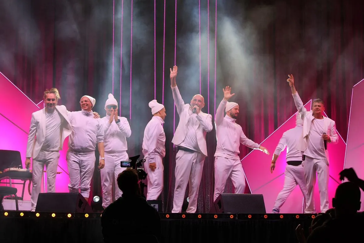 Artyści Kabaretu Neo-N&oacute;wka na scenie, w białych strojach, pozdrawiają publiczność. Wszyscy skecze na żywo!