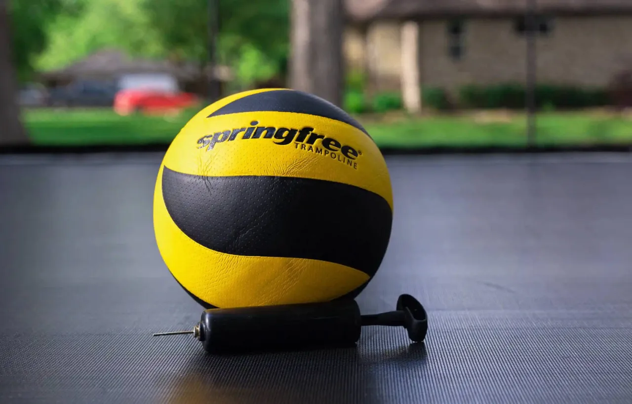 Ż&oacute;łto-czarna piłka i pompka. Dowiedz się, jak napompować piłkę bez pompki, używając tej prostej metody.