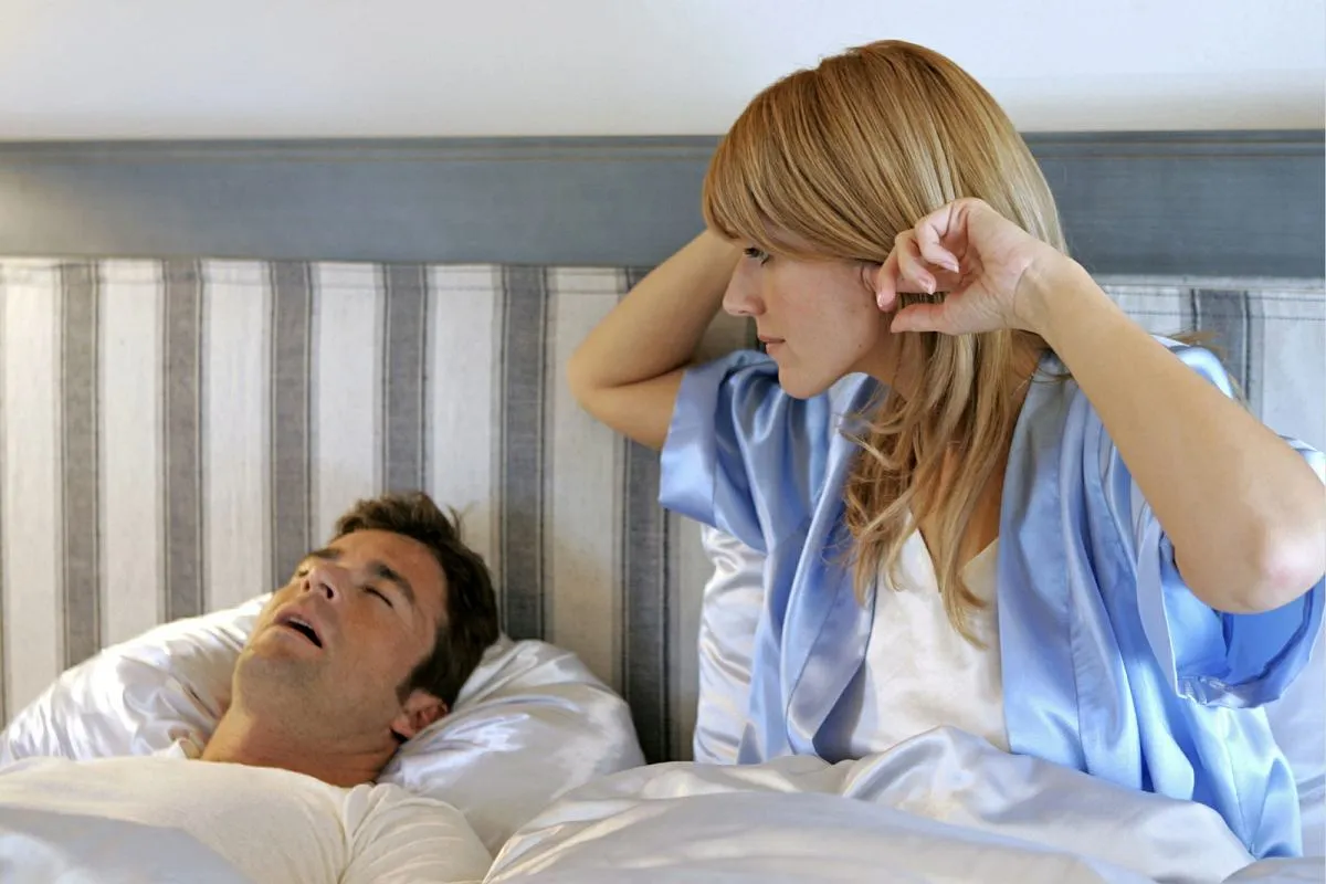 Para śpiąca, jedna osoba chrapie, druga zaniepokojona