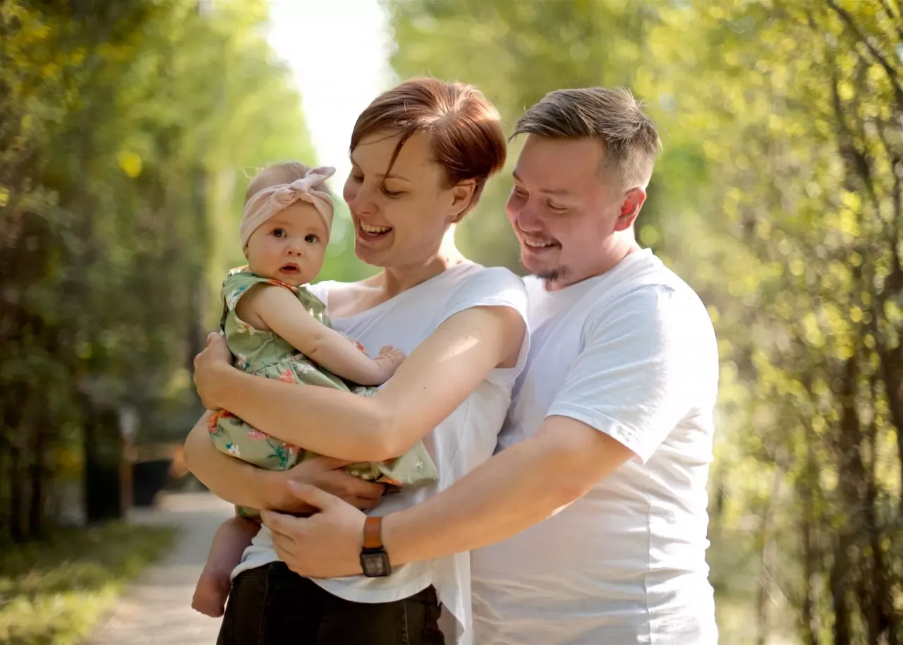 Szczęśliwa rodzina z niemowlęciem w parku. Dofinansowanie do żłobka do jakiego wieku? To pytanie nurtuje wielu rodzic&oacute;w.