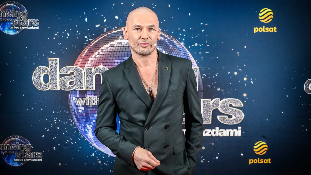 Tomasz w eleganckim garniturze pozuje na tle napisu 