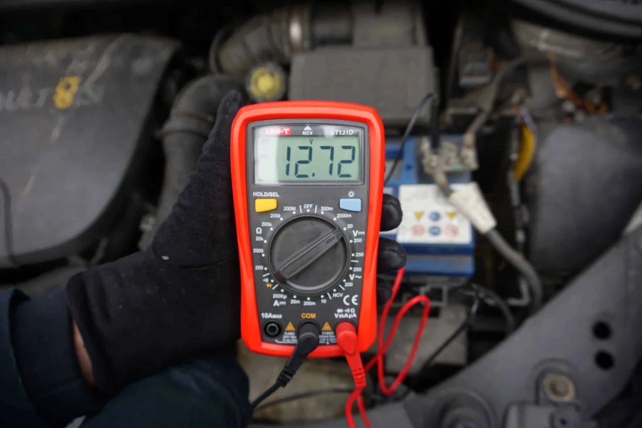 Multimetr pokazuje 12.72V, sprawdzając, czy alternator ładuje akumulator na postoju.