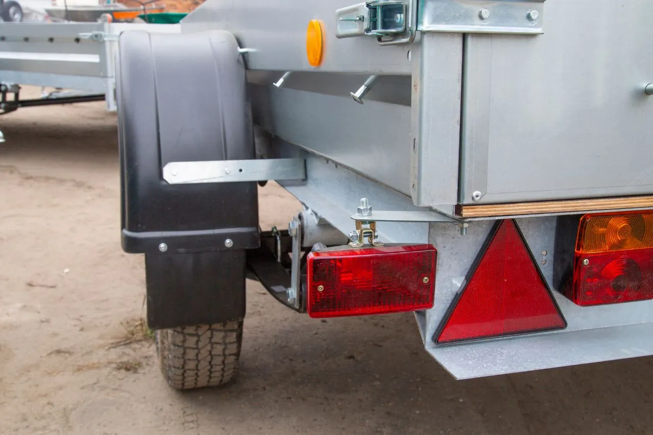 Widoczne są dwa czerwone światła pozycyjne z tyłu przyczepy.