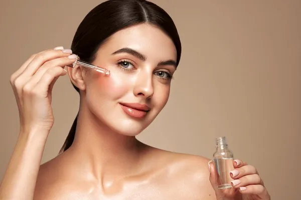 kobieta aplikująca serum na twarz z bliska