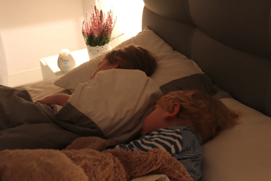 zmartwiony rodzic siedzący przy łóżku śpiącego dziecka w nocy