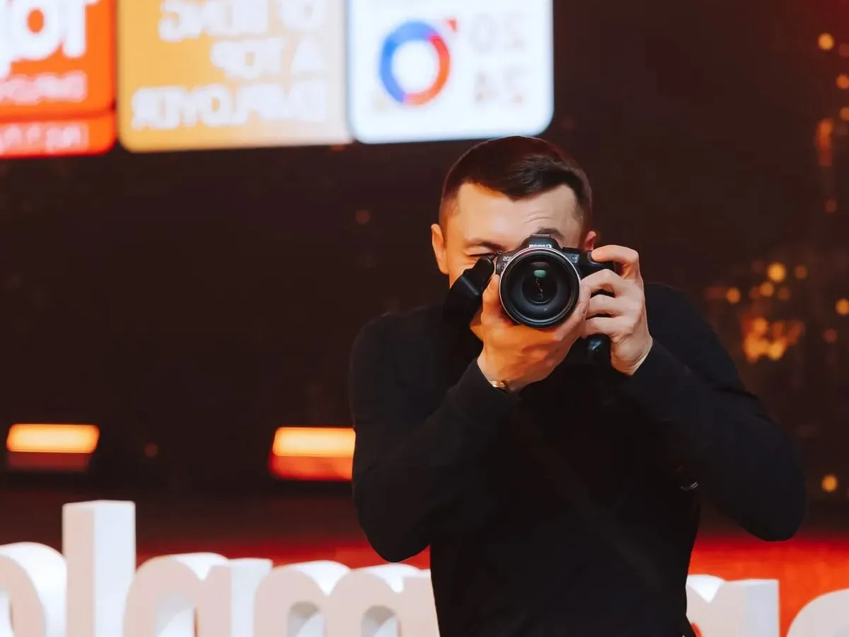 Fotograf z aparatem w rękach, gotowy do uwiecznienia najlepszych momentów na imprezy, na które wynajmujemy fotografa.