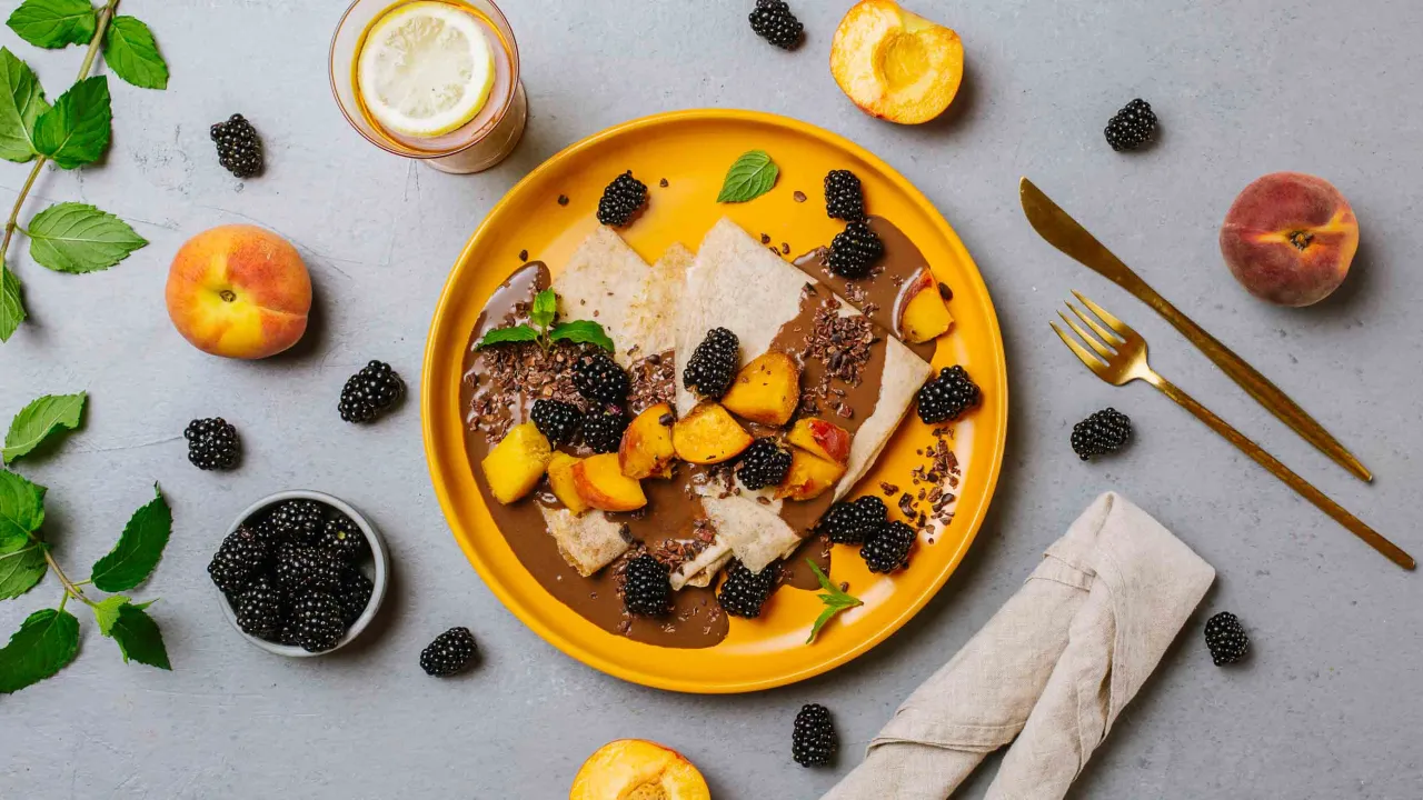 Naleśniki z czekoladą, jeżynami i brzoskwiniami. Pyszny deser, który może być zero kaloryczne, jeśli użyjesz odpowiednich składników.