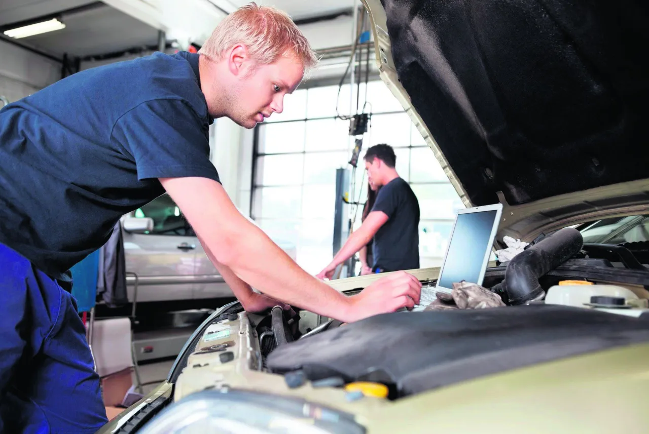 Mechanik samochodowy z laptopem i narzędziami